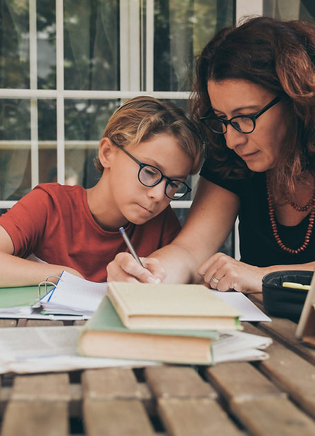 Adult woman assisting young boy with schoolwork at home.
