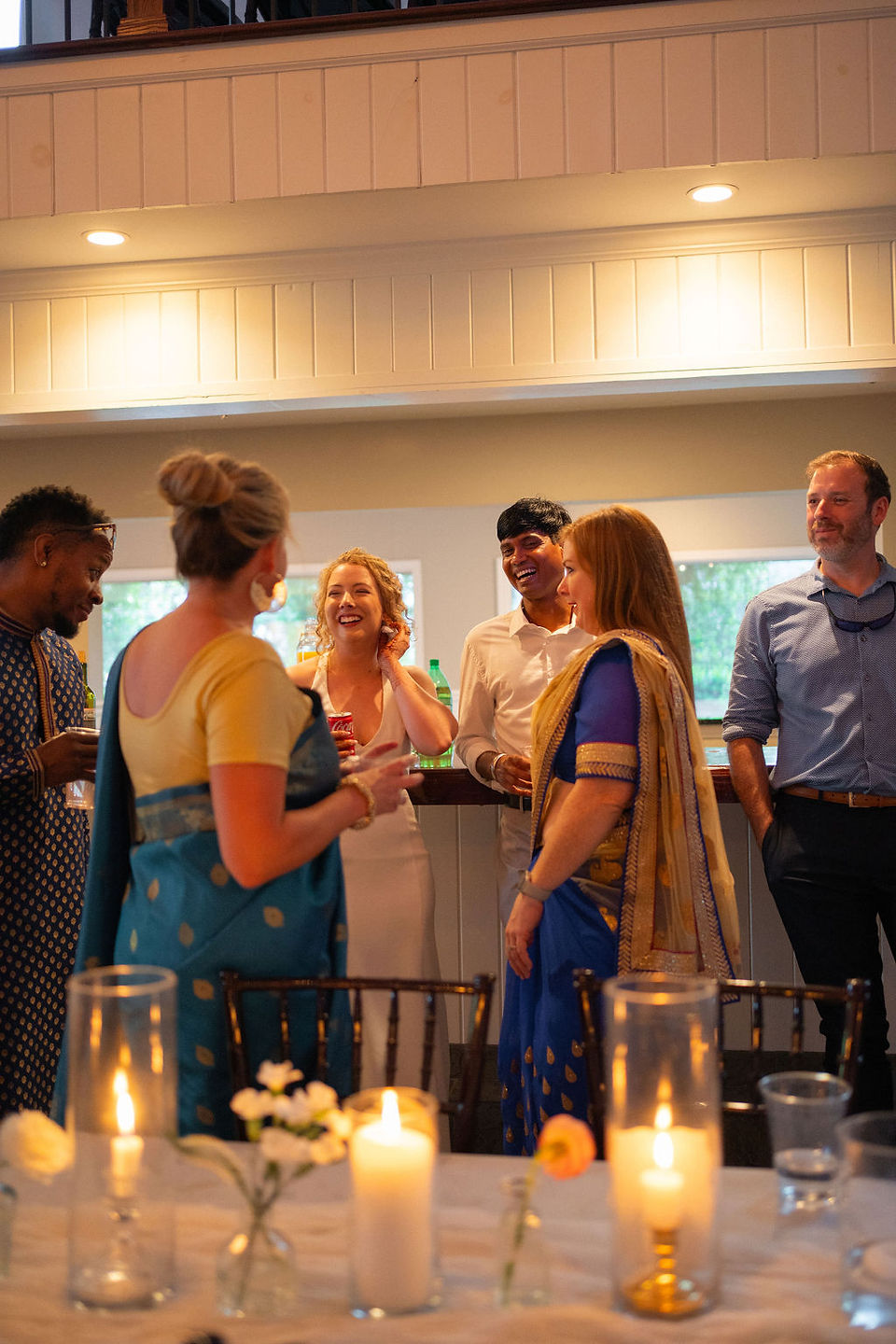 Bride and groom laughing with guests at bar