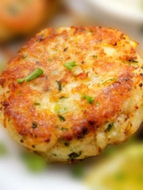 A close of a cooked cake cake with chopped parsley and garnished with lemon.