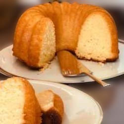 Slices of golden yellow pound cake on white plates that sit on a wooden table.