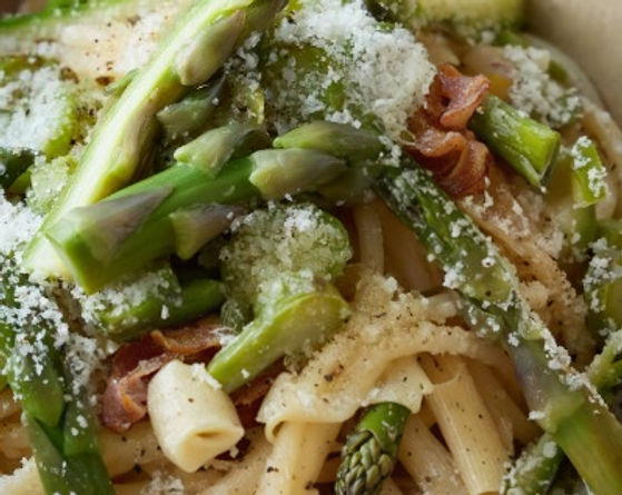 A close-up shot of a bowl of freshly made pasta with asparagus, parmesan cheese, and bits of bacon.
