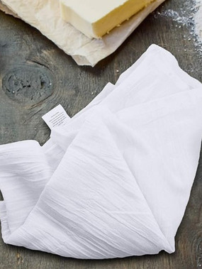 A close-up of a white linen dishtowel on a gray counter.