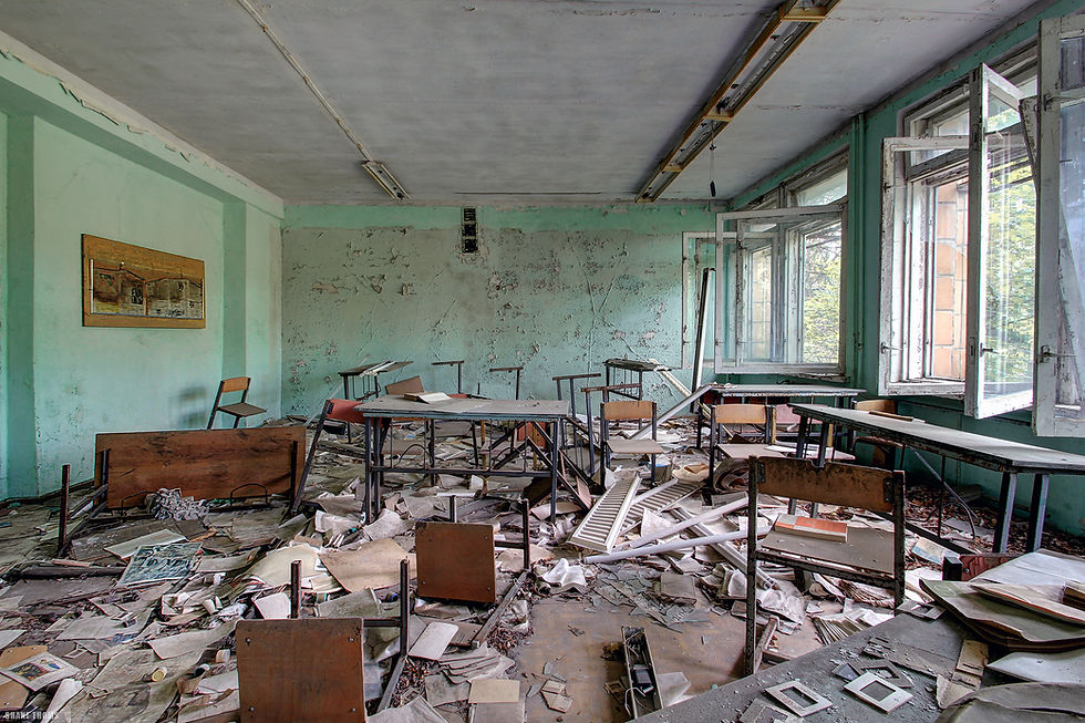 Abandoned classroom filled with overturned desks and scattered papers, revealing the remnants of a once-active learning environment.