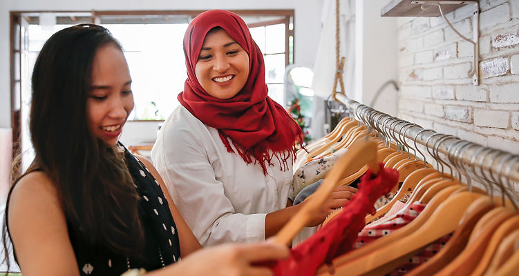 Two woman smiling looking at clothes