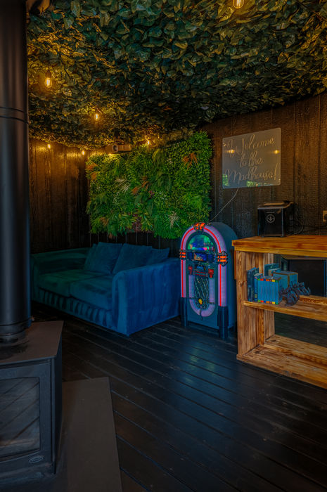 Private outdoor lounge with blue sofa, jukebox and covered bar at The Mad House