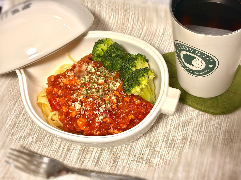 ドラえもんの秘密道具、畑のレストランを模したどんぶりにミートソーススパゲティとブロッコリーが入っている。横にドラえもんのカップに入った麦茶が添えてある。