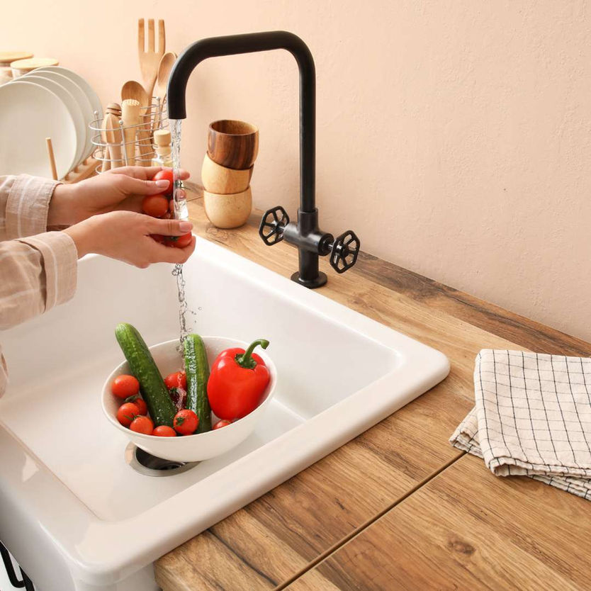women washing vegetables in a sink surrounded by wooden countertops