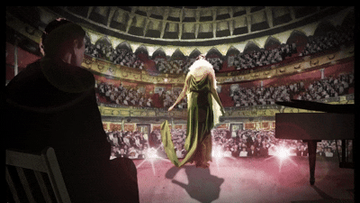 An animated woman in a green dress singing on stage in the 1920's