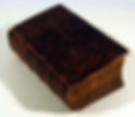 The last book in the pile: an old volume bound in mahogany brown binding