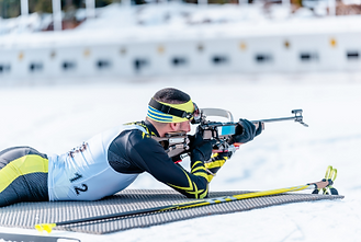Biathlet visiert liegend sein Ziel an
