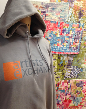 image of an artists' Exchange sweatshirt in front of colorful art on the wall