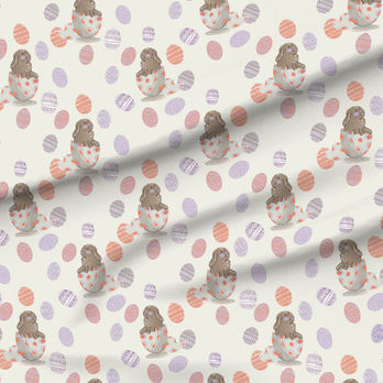 A slightly creased piece of fabric featuring baby bunnies sitting in easter egg shells, sticking out their tongues.
