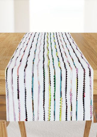 A slightly creased piece of fabric featuring punky colorful zigzag trimmings arranged in stripes on white.