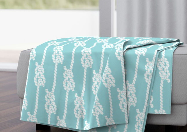 A slightly creased piece of fabric featuring white knotted ropes on a blue background by lenes_linien.