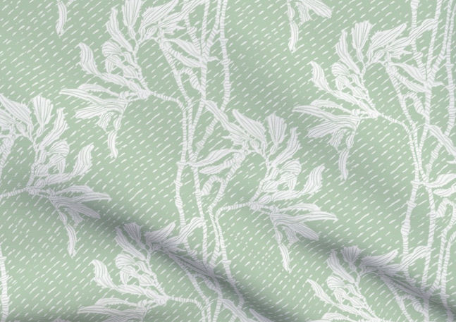 A slightly creased piece of fabric featuring an elegant duotone design of sea kelp fronds in a blockprint style.