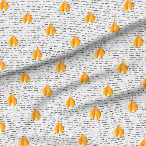 A slightly creased piece of fabric featuring falling yellow ginkgo leaves on a white-grayish background with black dashed lines by lenes_linien.