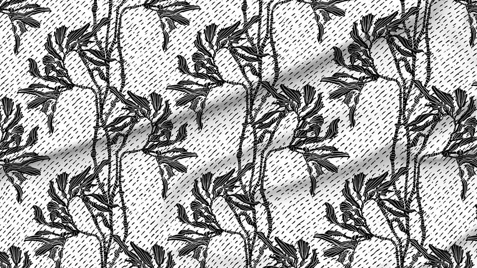 A slightly creased piece of fabric featuring an elegant duotone design of sea kelp fronds in a blockprint style.