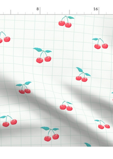 A slightly creased piece of fabric featuring a design of red cherries with green stems amd a green grid on white by lenes_linien