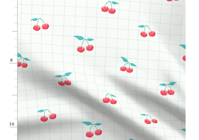 A slightly creased piece of fabric featuring a design of red cherries with green stems amd a green grid on white by lenes_linien