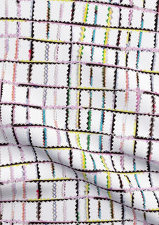 A slightly creased piece of fabric featuring punky colorful zigzag trimmings arranged in grid format on white.
