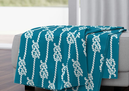 A slightly creased piece of fabric featuring white braided ropes with maritime knots on a teal background by lenes_linien.