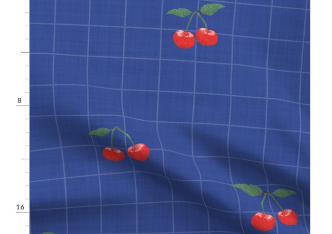 A slightly creased piece of fabric featuring a design of red cherries with green stems and a grid on elegant dark blue by lenes_linien