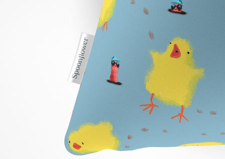 A slightly creased piece of fabric featuring fluffy yellow baby chicks and earthworms with sunglasses on a sky blue ground by lenes_linien.