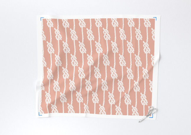 A slightly creased piece of fabric featuring white nautical ropes and knots on a dusty pink ground by lenes_linien.