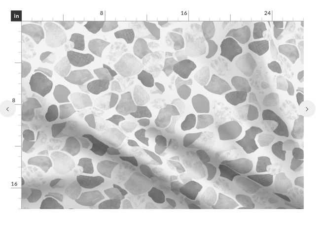 A slightly creased piece of fabric featuring abstract, textured shapes resembling mediterranean terrazzo stone floors.