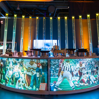 Curved bar station with Super Bowl football graphics and modern lighting at Exploratorium Media Party.