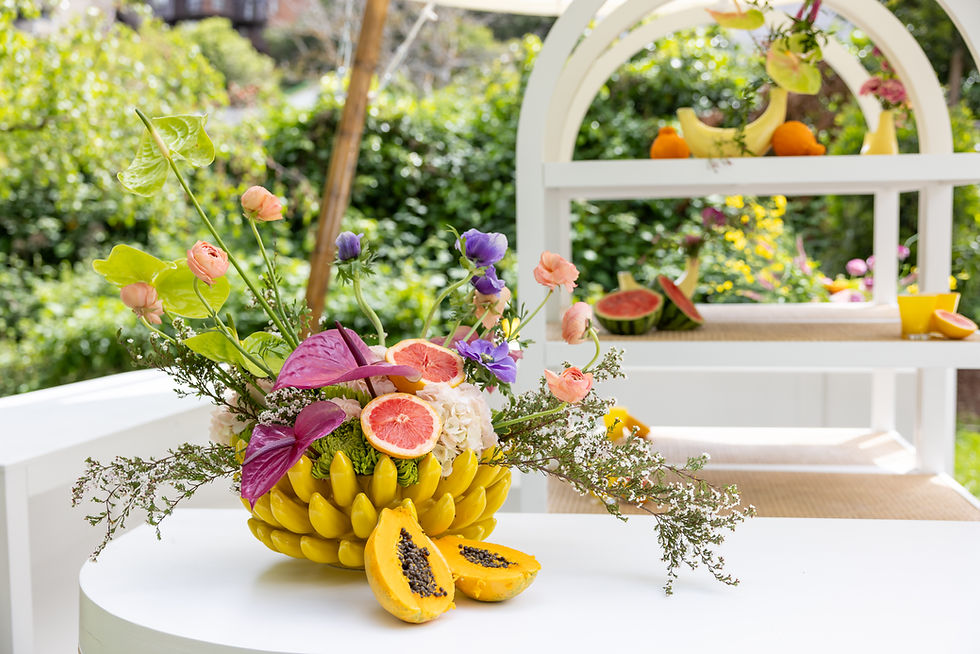 Fruit-themed floral centerpiece with grapefruit, papaya, and tropical flowers on white table