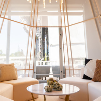 Minimalist event lounge pod with chandelier lighting and tepee frame