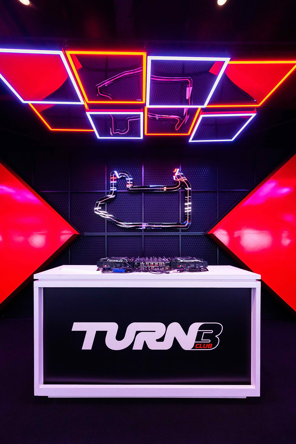 Turn 3 Club DJ booth at F1 event with neon ceiling and race track wall art