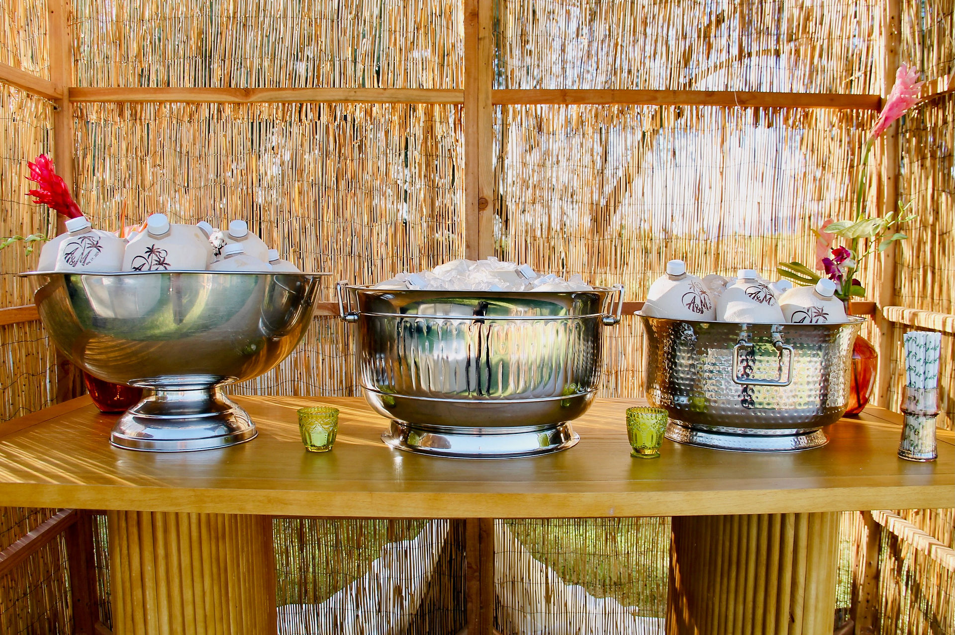 Beverage station with custom bottles on ice in metal coolers against a bamboo wall