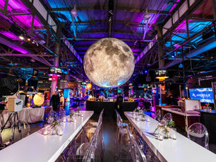 Experiential event design with moon installation, neon lighting, acrylic chairs, and immersive venue transformation