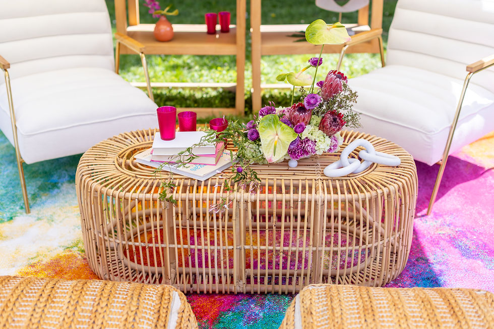 Colorful boho lounge setup with floral arrangement, rattan table, and white cushioned seating