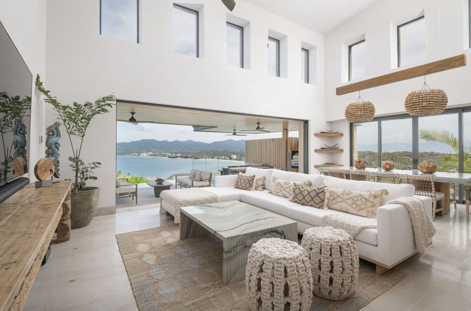Stunning living room with panoramic ocean views, contemporary furnishings, and soft neutral tones.