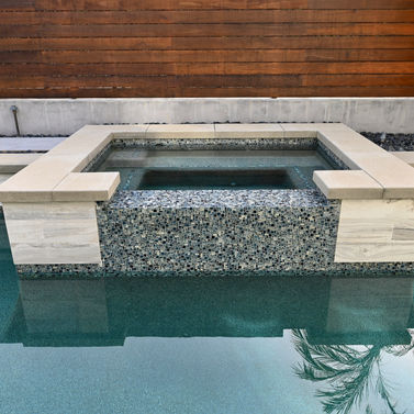 Poolside outdoor living space with luxurious hardscaping and serene coastal atmosphere.