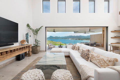 Luxury Vacation Home Family Room with Custom White Sofa Chaise, Custom Blue Stone Coffee Table, Fishtail Palm, View of the Ocean and Clearstory Windows