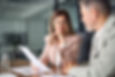 Two business executives discussing financial legal papers in office at meeting. Smiling fe