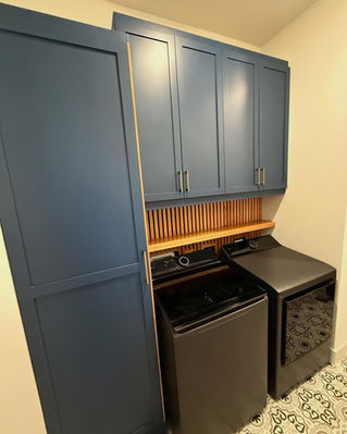 Custom laundry cabinets with workspace and solid wood paneling on wall