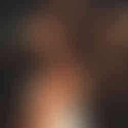 Young woman wearing a white dress, holding fabric in a field at sunset.