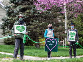 Tree people holding signs and a green ribbon connecting them