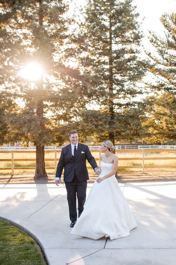 Portrait of a bride and groom walking and smiling during golden hour.