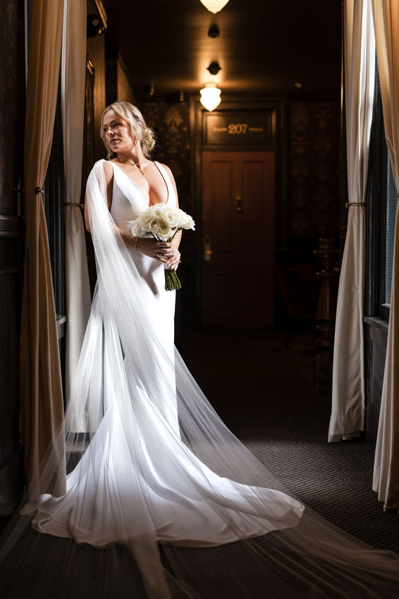 Moody portrait of a bride in a flowing dress in the hallway of the historic National Exchange Hotel in Nevada City, CA.