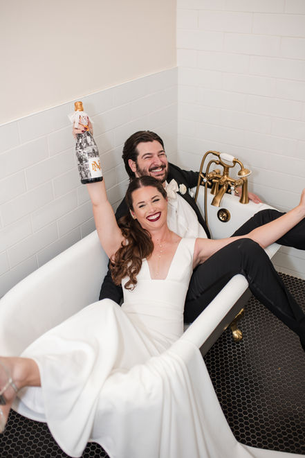 Portrait of bride and groom with champagne bottle in the bathtub at the historic National Exchange Hotel in Nevada City, CA.