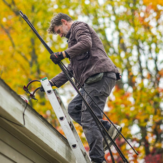 David Stover of Saint Nick's Chimney Service in Southern Maine, heads up a ladder to clean a chimney.