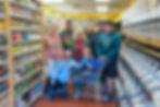 Three generations of the Ouellette family inside New Morning Natural Foods in Biddeford, Maine, standing between grocery shelves and bulk bins during the store’s 50th anniversary.