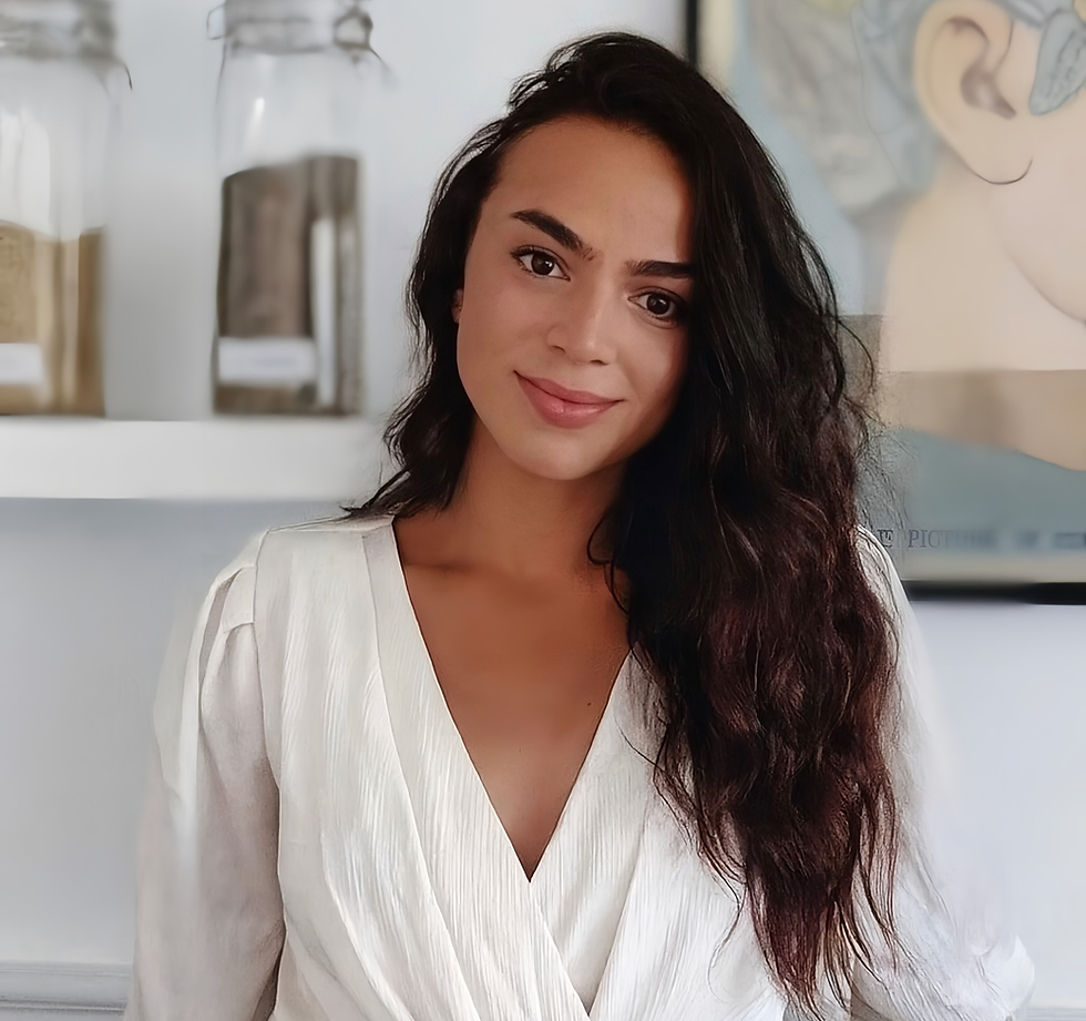Young woman with long dark hair smiles, wearing a white blouse.