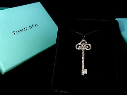 Tiffany & Co blue box with diamond encrusted platinum key with fleur de lis detail on top and chain on black velvet